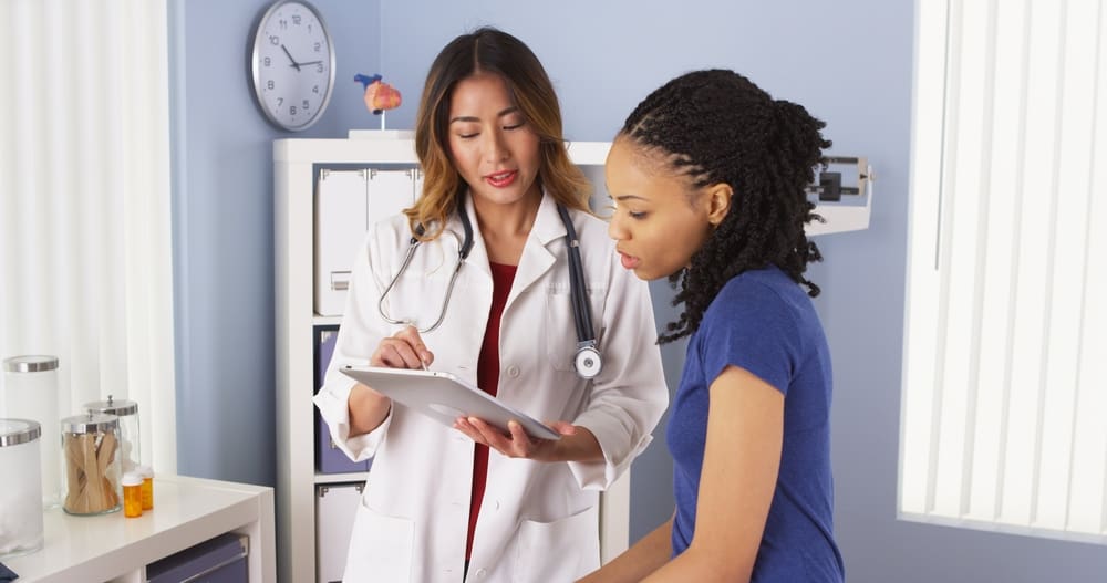 A doctor and patient (both female) talking and looking together at a tablet