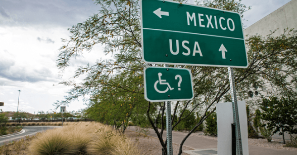 A road sign that reads Mexico with an arrow to the left, and USA with an arrow pointing forward.