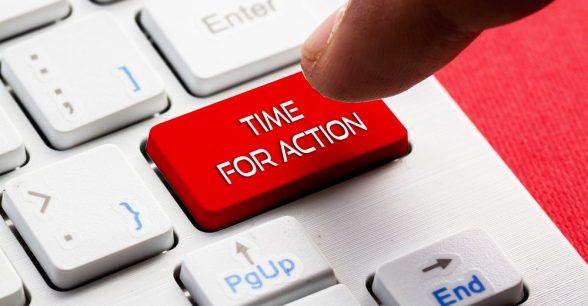 Close-up photo of a small section of a compute keyboard. There is a bright red button that reads "Time for Action." A person's finger hovers over this key, as if about to press it.