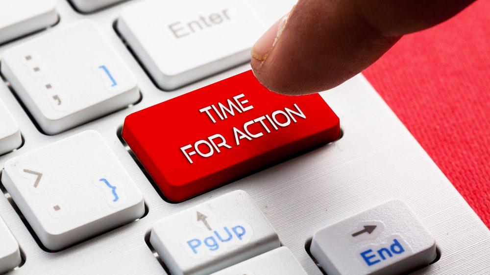 Close-up photo of a small section of a compute keyboard. There is a bright red button that reads "Time for Action." A person's finger hovers over this key, as if about to press it.