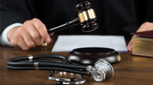 Judge in position to bang a gavel, with a piece of paper and a stethoscope in front of him.