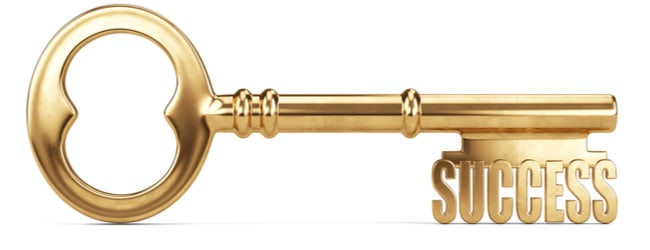An old-fashioned gold key with teeth that read "success."