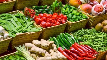 Fresh, colorful fruits and vegetables displayed in bulk in boxes.