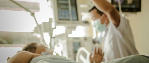 A blurred photo of a doctor and patient in a hospital room.