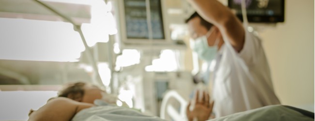 A blurred photo of a doctor and patient in a hospital room.