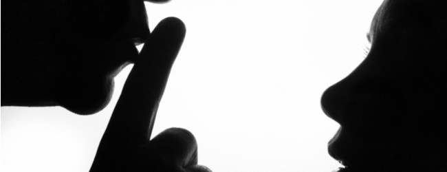 A silhouette of a person holding his fingers to his lips to shush a silhouette of a person looking up at them.