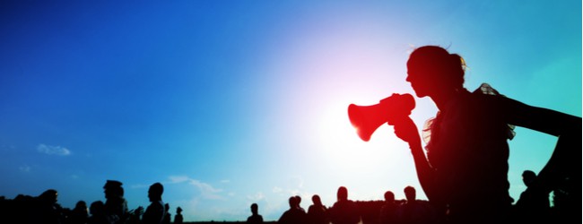 A silhouette of a person speaking into a megaphone, surrounded by other silhouettes.