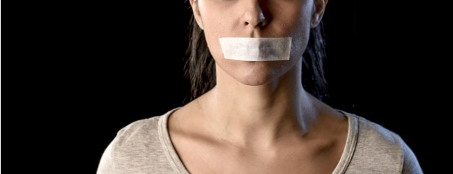A female-presenting person shown from the nose to the neck, with duct tape over her mouth, indicating silence.