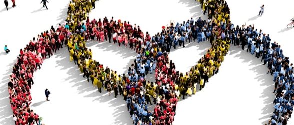 Three partially formed circle made up of an aerial view of people. In one circle, people are dressed in red, in another, they're dressed in blue, and in the third, green. Where the circle intersect, the clothing is multicolored.