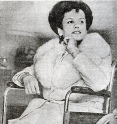 Bobbie Lea Bennett, a trans woman, sits in a wheelchair. She is wearing a white coat with a fur collar.