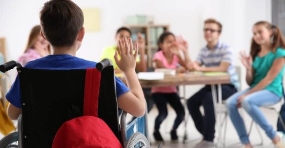Boy in wheelchair with classmates at school