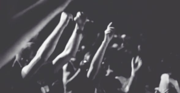 A black and white blurred photo of protestors. Only their arms are visible.