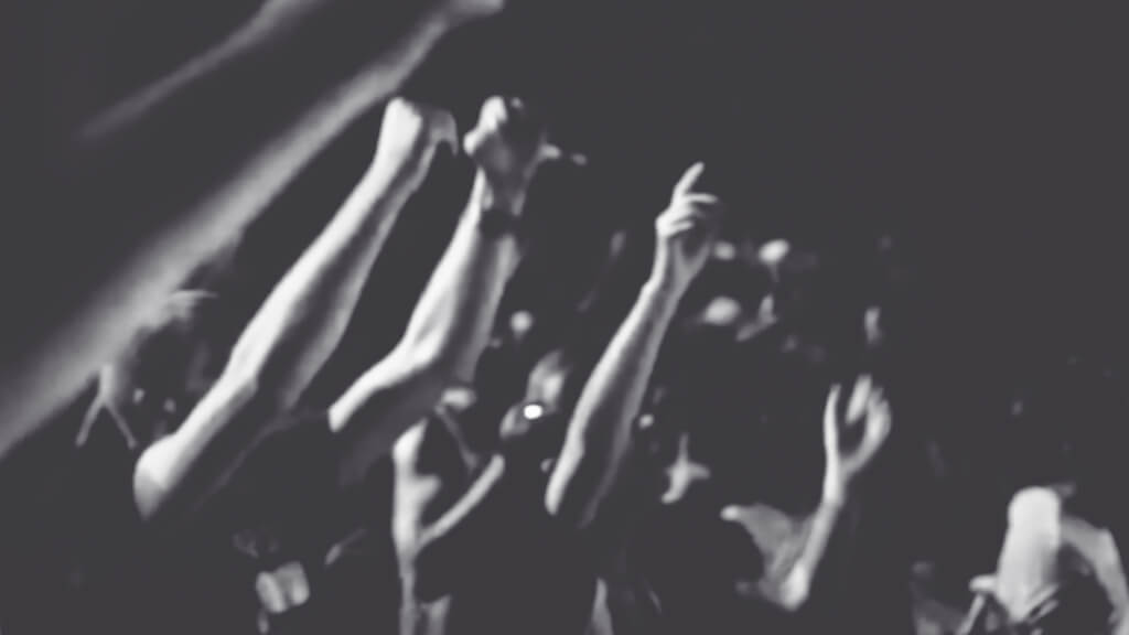 A black and white blurred photo of protestors. Only their arms are visible.