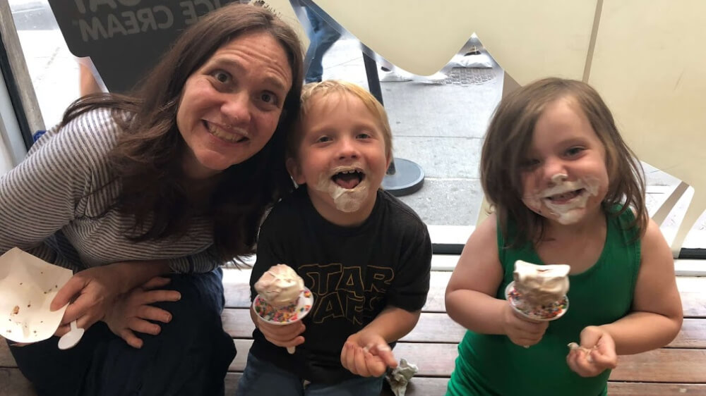 Photo of Heather and her two children, both with ice cream on their faces.