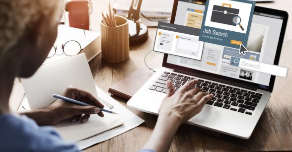 A person sitting at their desk using a laptop to search for a job.