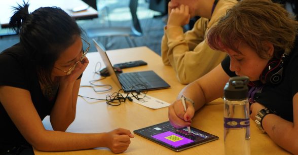 Rachel watches a DO-IT Scholar edit a video on an iPad.