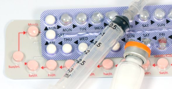Two packs of birth control pills and a syringe with a medicine bottle