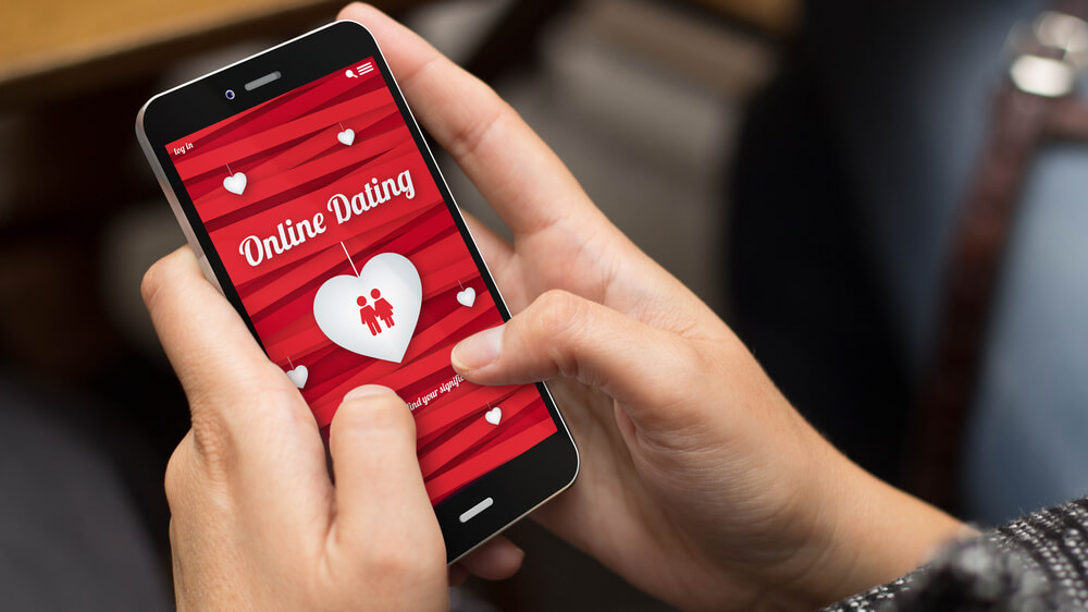 Photo of a person's hands holding a smartphone that has an online dating app opened