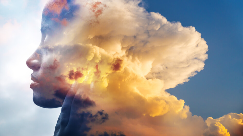 A photo of a black person with their eyes closed fades into a photo of clouds in the sky.
