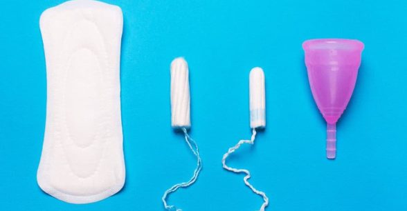 A menstrual pad, two tampons, and a menstrual cup against a bright blue background.