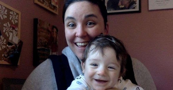 Photo of Robin holding Evren, a smiling baby.