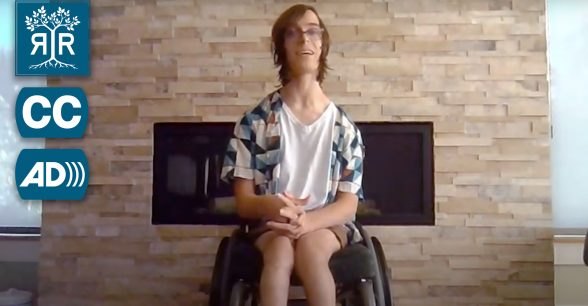 Braxton sits in their wheelchair in front of their fireplace.