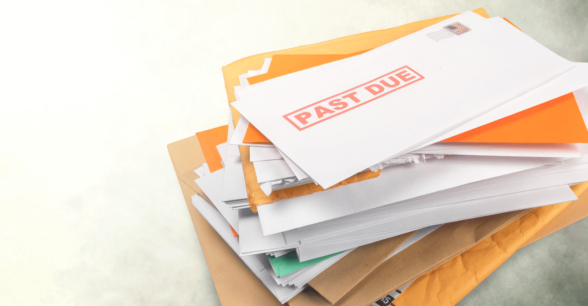 A stack of envelopes with one on the top that says "past due" in bold red letters.