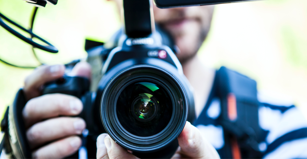 A man holding a camera, close up at the lens.