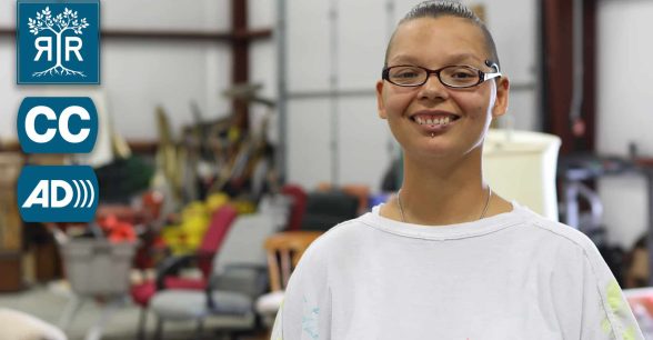 A woman wearing glasses is smiling at the camera.