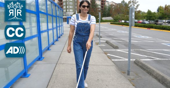 Amandeep walking on the sidewalk with their white cane