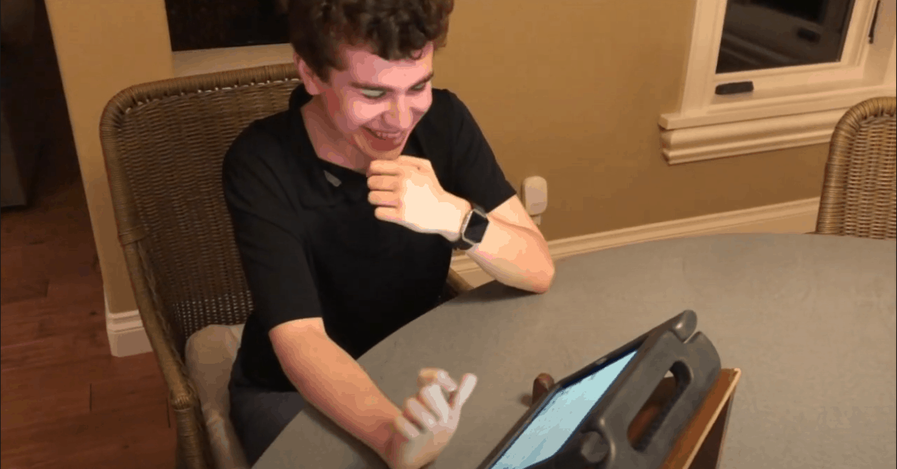 Grant smiles as he types on his communication device.