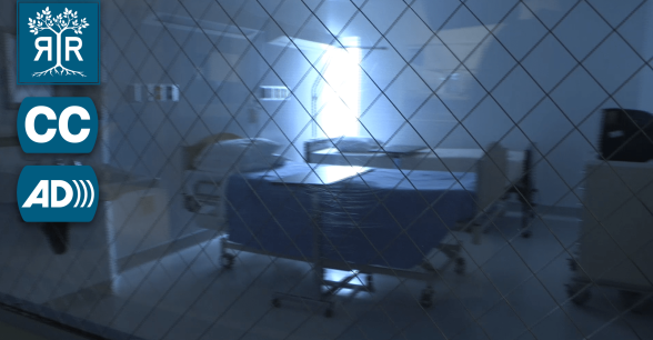 The view looking through a hospital window of a room with 2 hospital beds.