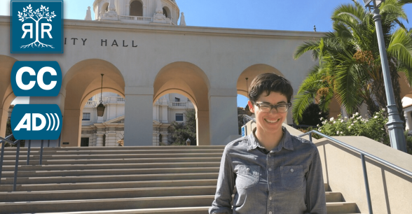 Carrie is smiling, behind her is a building with the title of "City Hall".