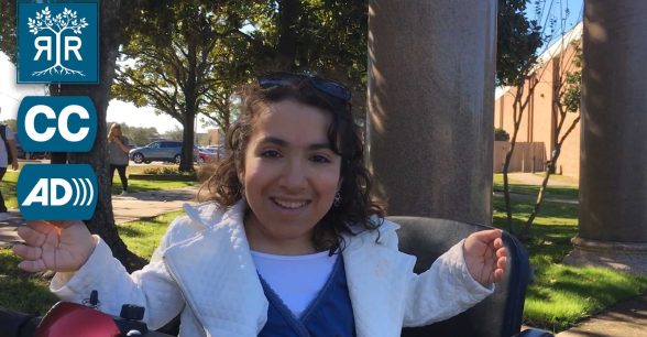 Cuquis is sitting in her wheelchair outside and smiling at the camera
