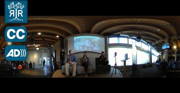 And panoramic view of an interview. Three people are sitting in chairs with a projecting behind them showing an online meeting.