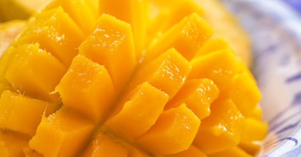 Close up of a ripe, juicy mango that is peeled and sliced to the seed but still attached.