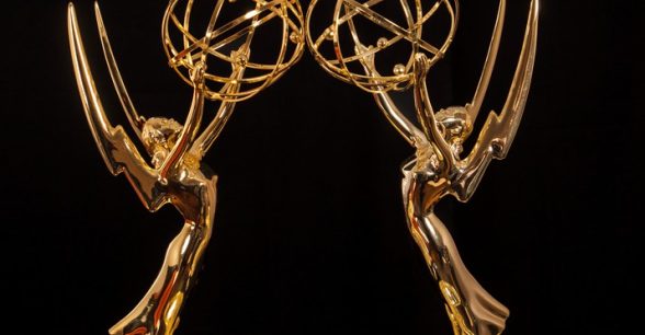 Black background. Two gold, winged Emmy statues stand facing each other.