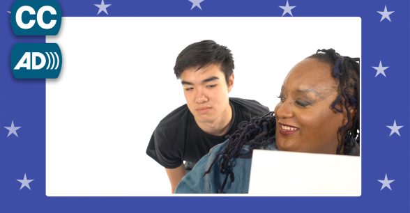 Two people. One leans over the shoulder of the other.