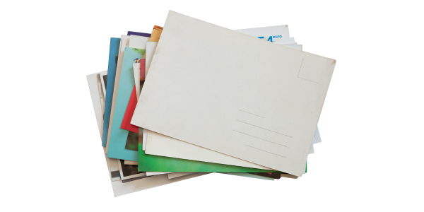 A pile of mail that includes envelopes, postcards, and advertisements. The pieces of mail are green, red, cerulean, robin’s eggs blue, white, and yellow. The top post card is blank showing only white card stock, thin black lines where an address would go, and a thin black outline for stamp placement.